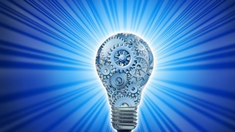 A light bulb filled with different sizes of gears emanates blue light