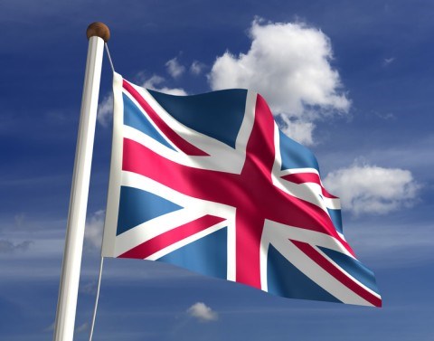 The United Kingdom flag on a flag poll waving in front of a blue sky with clouds