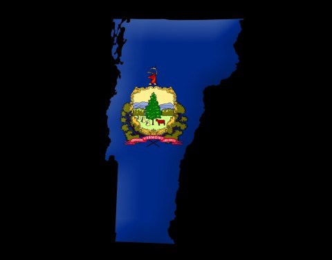 State of Vermont colored in solid blue with the Vermont seal in the middle of the state on a black background