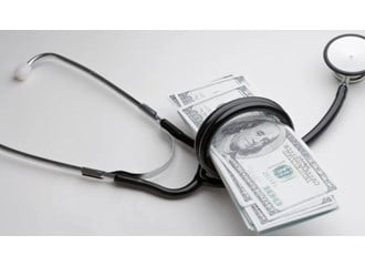 A blackstethoscope wrapped around a small stack of one-hundred-dollar bills.