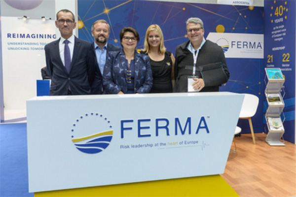 Group of people standing behind FERMA counter at trade show