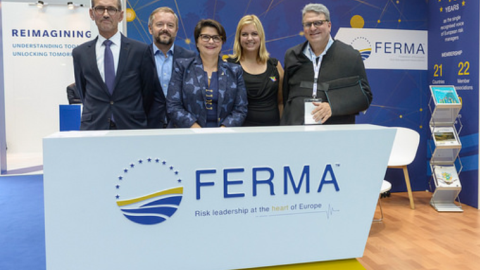 Group of people standing behind FERMA counter at trade show