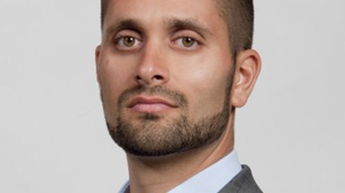 Headshot of Hanni Ali in a grey suit and pale blue shirt
