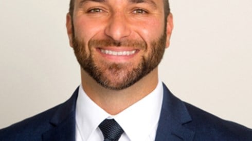 Headshot of Brad Sforza wearing a navy blue suit, white shirt, and navy blue tie