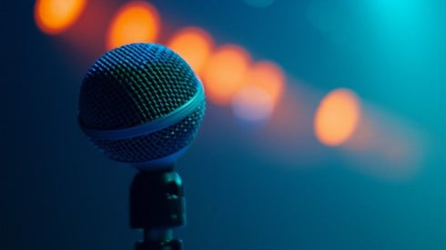 A microphone with orange spotlights and a blue background.