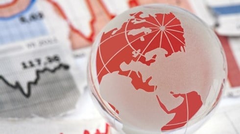 Red and white globe sitting on top of investment data graphs on paper