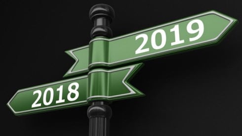 Street sign pole with 2 green arrows marked 2018 pointing left and 2019 pointing right