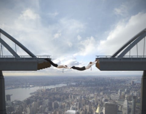 People hanging between gap in bridge
