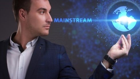Businessman looking at a hologram of a globe in his hand and the word MAINSTREAM extending from his face to the equator line