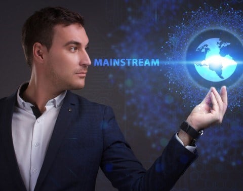 Businessman looking at a hologram of a globe in his hand and the word MAINSTREAM extending from his face to the equator line