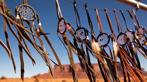 Dreamcatchers hung in a row with a desert plateau in the background