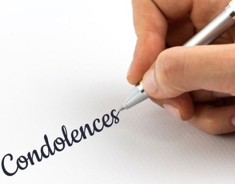 The word condolences being handwritten on a white piece of paper 