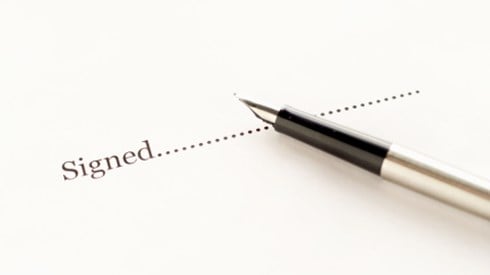 Fountain pen lying on white paper that reads signed