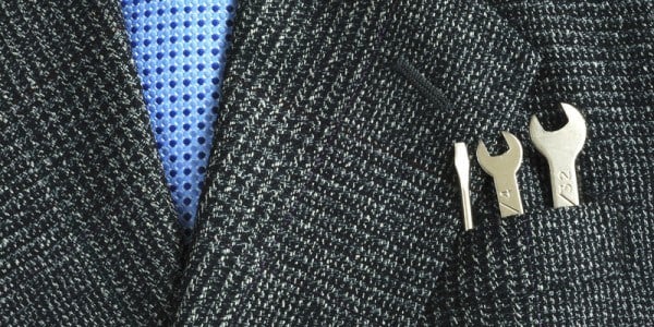 Closeup of businessman´s tie and jacket pocket containing a flat head screwdriver and two different sized wrenches