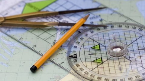 Navigational course plotting tools with compass and pencil laying on top of a map