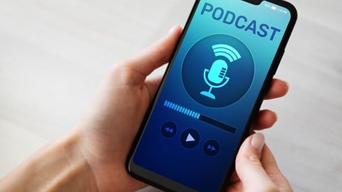 Podcast Word and Microphone Logo on Smartphone Screen on Device Held in Hand of Woman