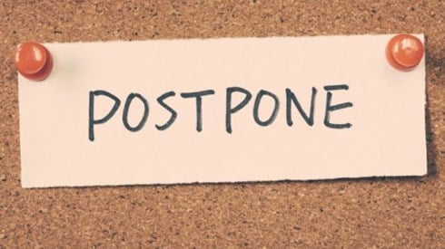 A card reading "postpone" pinned to a bulletin board