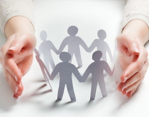 A set of protective hands around paper chain people in a circle