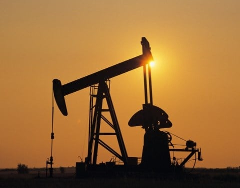 A silhouette of an oil drill against a sunset sky