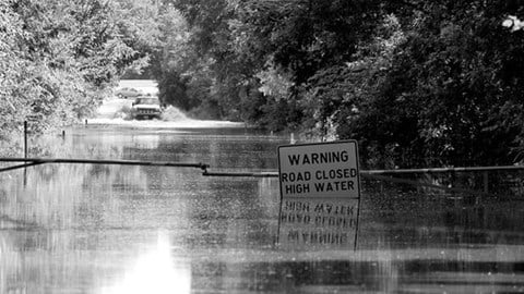 Flooded road with a sign reading "Warning: Road Closed High Water"