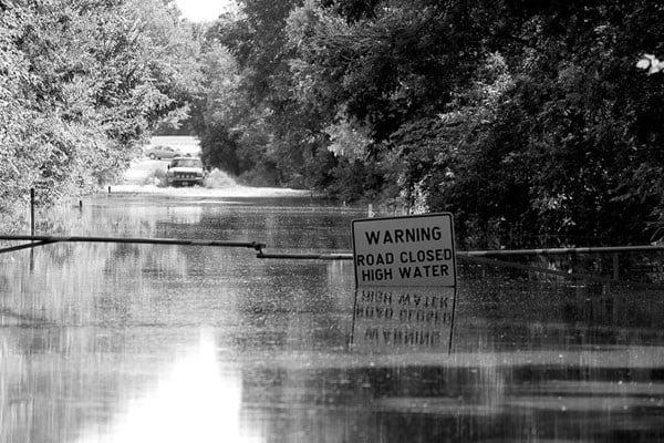 Flooded road with a sign reading "Warning: Road Closed High Water"