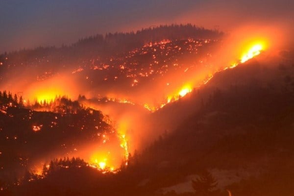 Wildfire viewed at night from distance burning in hills and valleys