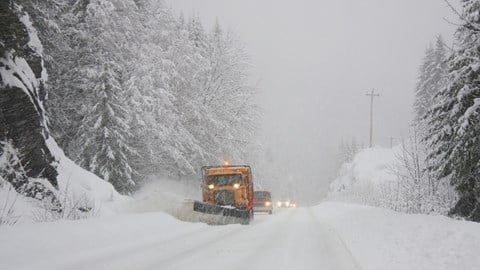 Two snowplows on a road during a winter storm
