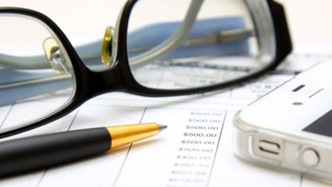 Financial statement under review with eyeglasses, black and gold pen, and smartphone on top