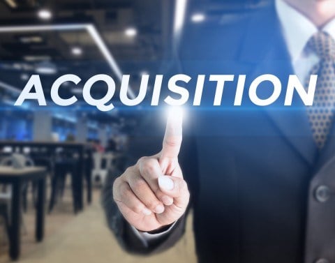 Businessman pointing with index finger to floating text of the word Acquisition