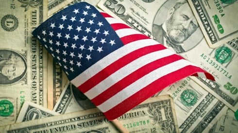 A small American Flag on top of a pile of US money
