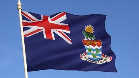 Cayman flag flying on a pole with a blue sky background