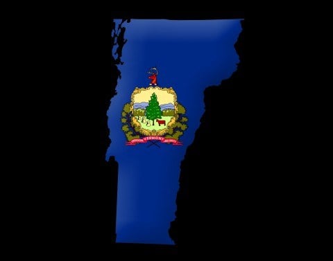 State of Vermont colored in solid blue with the Vermont seal in the middle of the state on a black background