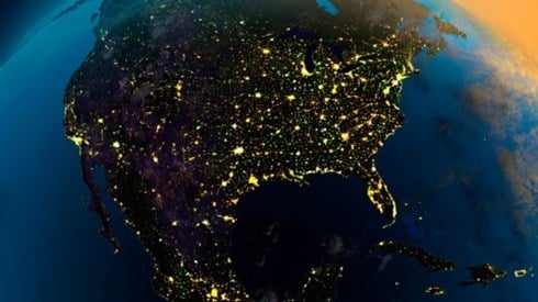 Global view of North America at night as viewed from space with lights showing in the cities with sunrise approaching in the east
