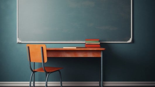 School desk sitting in front of chalkboard