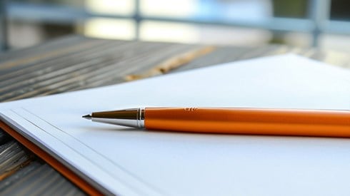 An orange pen sitting on a blank contract.