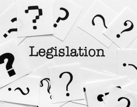 Several pieces of white paper with black question marks surrounding the word legislation