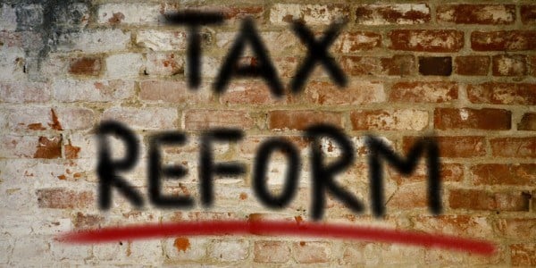 The words TAX REFORM are spray painted on a deteriorating brick wall