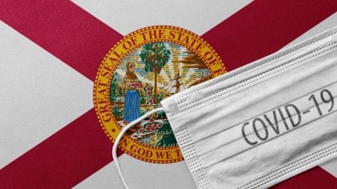 The Florida flag with a medical mask and COVID-19 written on it