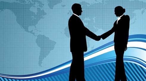 Silhouette of a man and woman shaking hands in front of world map