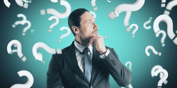 Businessman pondering surrounded by question marks