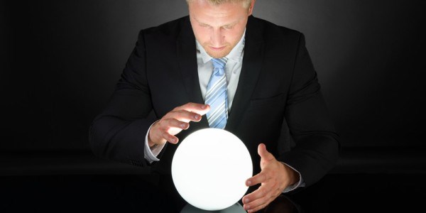 Man in black suit looking at glowing crystal ball with his hands surrounding it