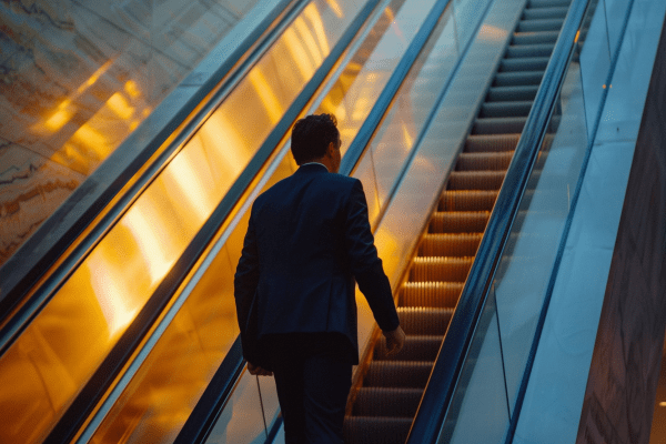 Businessman riding escalator to next floor