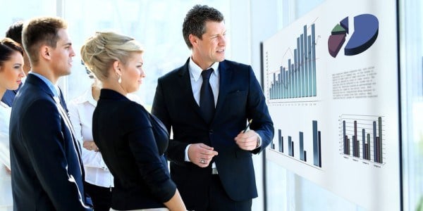 Business people meeting looking at charts and graphs displayed on screen
