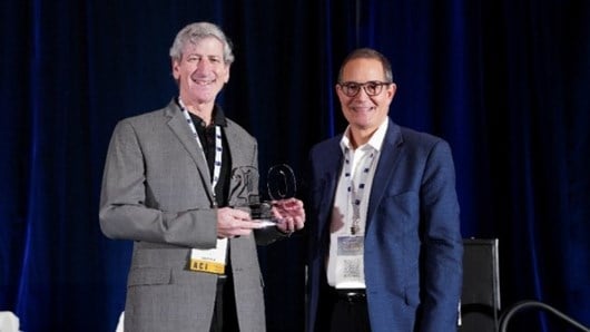 Business Insurance Publisher Keith Kenner presents ICCIE Executive Director Mitch Cantor with a special commemorative award to mark ICCIE's 20th Anniversary at World Captive Forum 2024