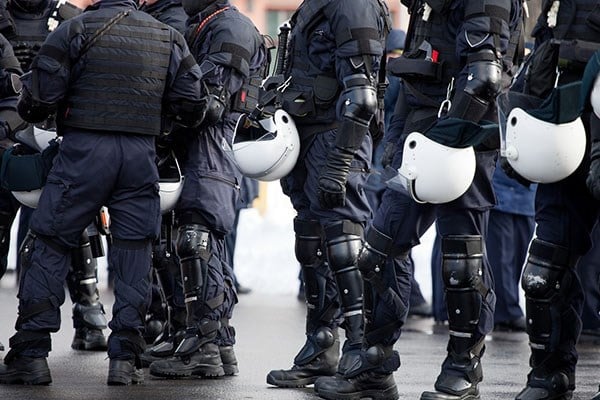 Line of riot police holding helmets in hand