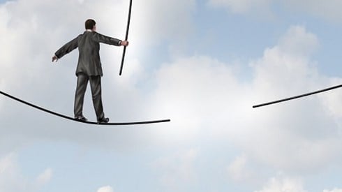 A businessman in the clouds is walking on a tightrope using a balancing pole and will approach a section that has disappeared