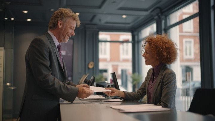 businessman handing a paper to a bank manager