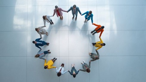 a group of businesspeople standing in a circle holding hands