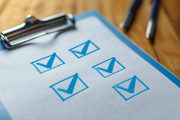 blue clipboard with checked boxes on top of a desk