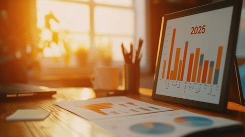 Various charts and graphs on an office desk with the year 2025 above a bar chart